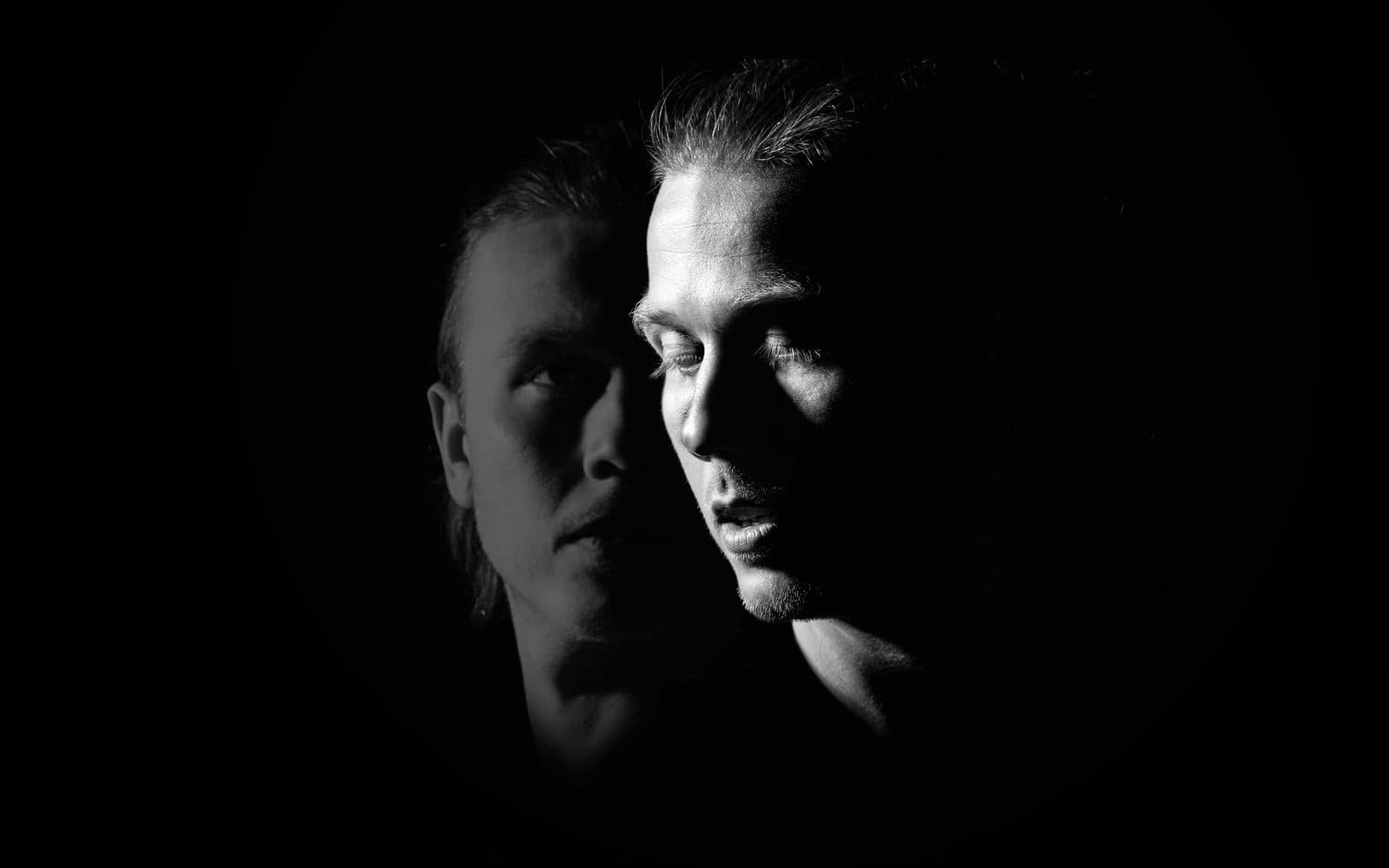 Two faces emerging from darkness — promotional image for the storytelling concert GLENN