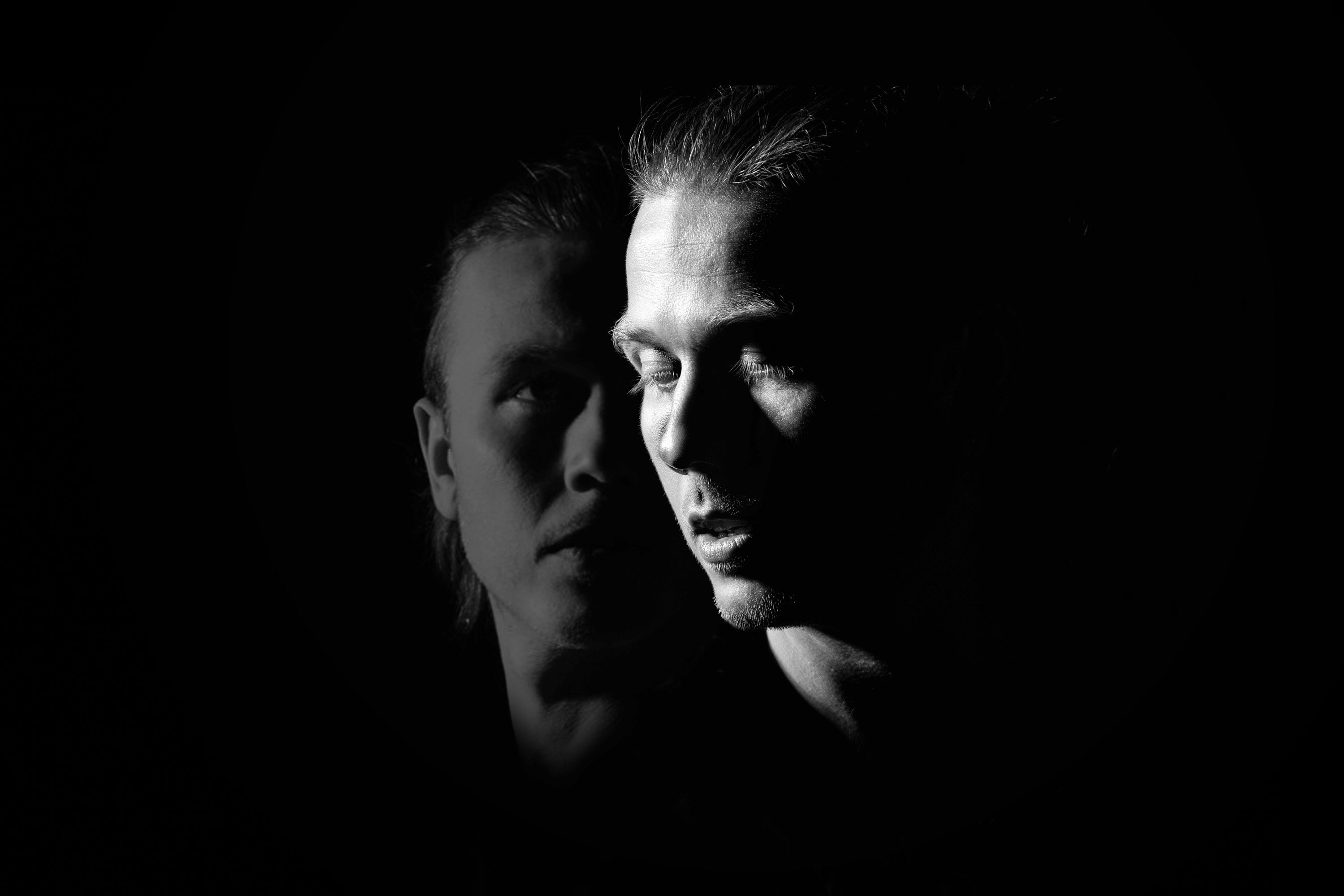 Two faces emerging from darkness — promotional image for the storytelling concert GLENN