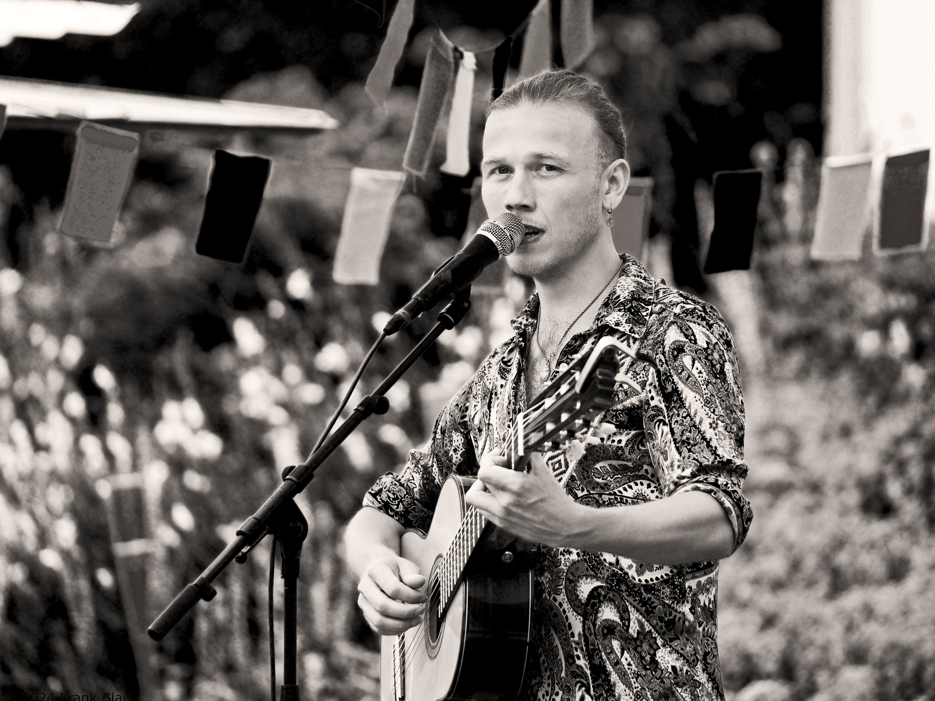 Erik Sjöholm singing into a microphone at an outdoor festival, audience behind